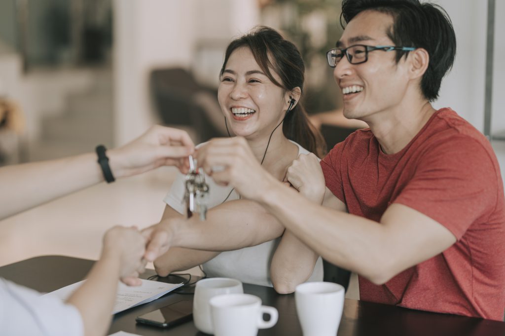 asian chinese real estate agent shake hand and hand over the house keys to his clients at the kitchen about the policies | 利嘉閣地產有限公司