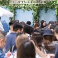Crowd of people at a Deep Water South booth decorated with green vines and a white umbrella