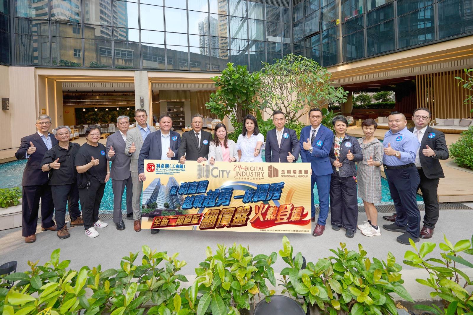 Group of professionals posing outdoors with a large promotional banner in front of a modern glass building.