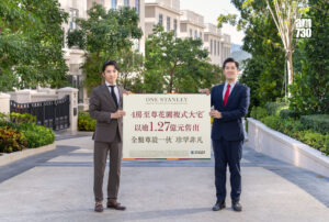 Two men in suits hold a large sign advertising a property development outdoors with the am730 logo visible