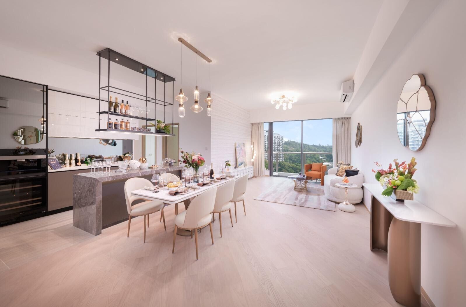 Open-plan living and dining area with a marble kitchen island, hanging pendant lights, and a long dining table set for dinner.