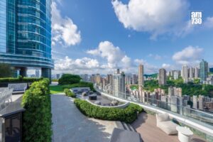 Rooftop terrace with outdoor seating glass front skyscraper on the left and a city skyline under a blue sky