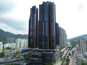 Urban skyline with a cluster of tall glass towers a rail line at street level and green hills in the background