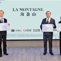 Three professionally dressed individuals stand side by side each holding a certificate in front of a light blue backdrop with the text LA MONTAGNE and logos below