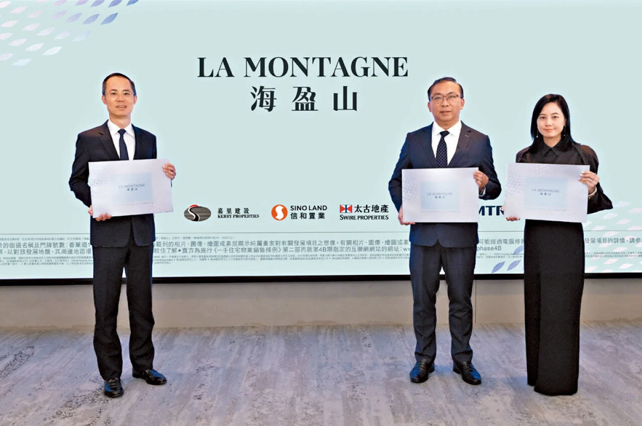 Three professionally dressed individuals stand side by side, each holding a certificate in front of a light blue backdrop with the text 'LA MONTAGNE' and logos below.