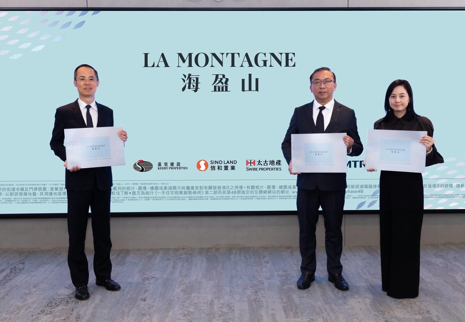 Three professionals in suits hold certificates while standing in front of a light blue backdrop that reads 'LA MONTAGNE' with logos below.