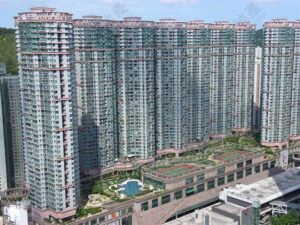 Tall residential complex of interconnected high rise buildings with green balconies and a central courtyard featuring a pool