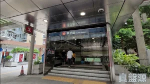5662838be2e349879bc343c6c84e2ae9 | 利嘉閣地產有限公司 Mei Foo Station entrance with glass doors red MTR logo and people walking up the stairs under a metal canopy