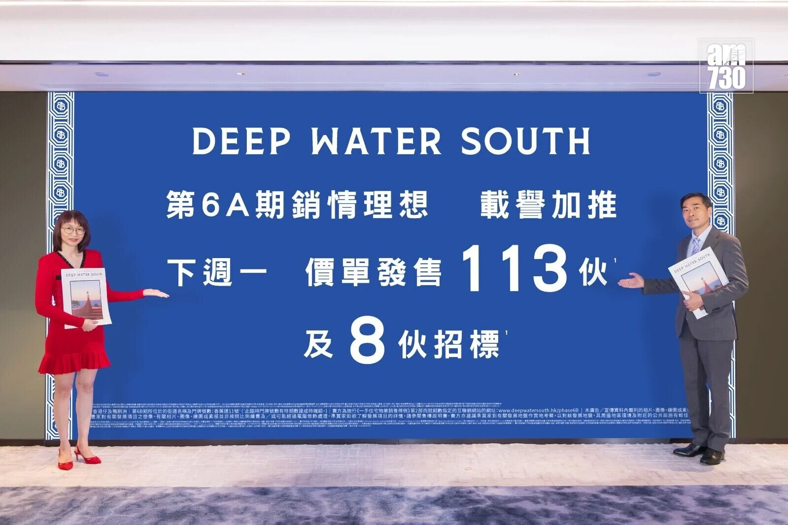 Two presenters stand on either side of a large blue display board reading 'DEEP WATER SOUTH' with Chinese text, holding brochures.