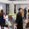 Group of people in a modern showroom admiring a detailed scale model of a high rise building