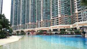 Tall resort style pool with palm trees and dozens of high rise residential towers in the background