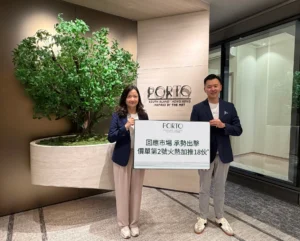 Two people in blazers stand in a modern lobby holding a large sign with the PORTO logo and Chinese text