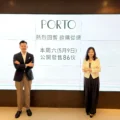 Two professionalsman in a suit and woman in a blazerstand in front of a large screen displaying PORTO and Chinese text