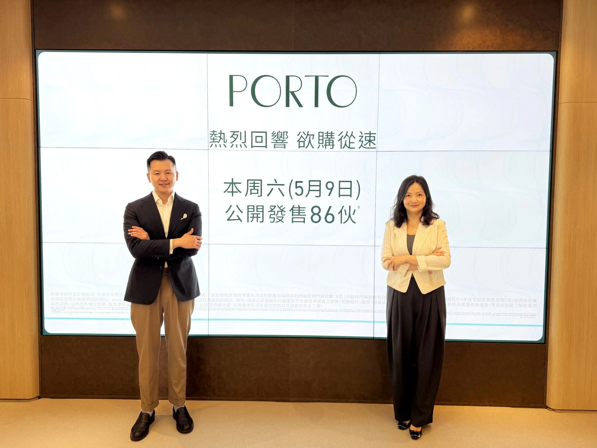 Two professionals—man in a suit and woman in a blazer—stand in front of a large screen displaying PORTO and Chinese text.