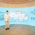 Man in light blazer standing in front of a blue curved real estate display with floor plan diagram and HIGHWOOD signage