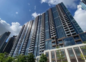 Tall modern glass high rise under a blue sky with clouds am730 logo in the top right corner