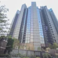 Tall modern glass skyscraper viewed from street level, with trees in the foreground and AM730 logo in the top-right corner.