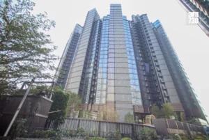Tall modern glass skyscraper viewed from street level with trees in the foreground and AM730 logo in the top right corner