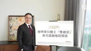 Man in a dark suit and red tie poses beside a large sign with Chinese text and the Jardini logo in a bright room