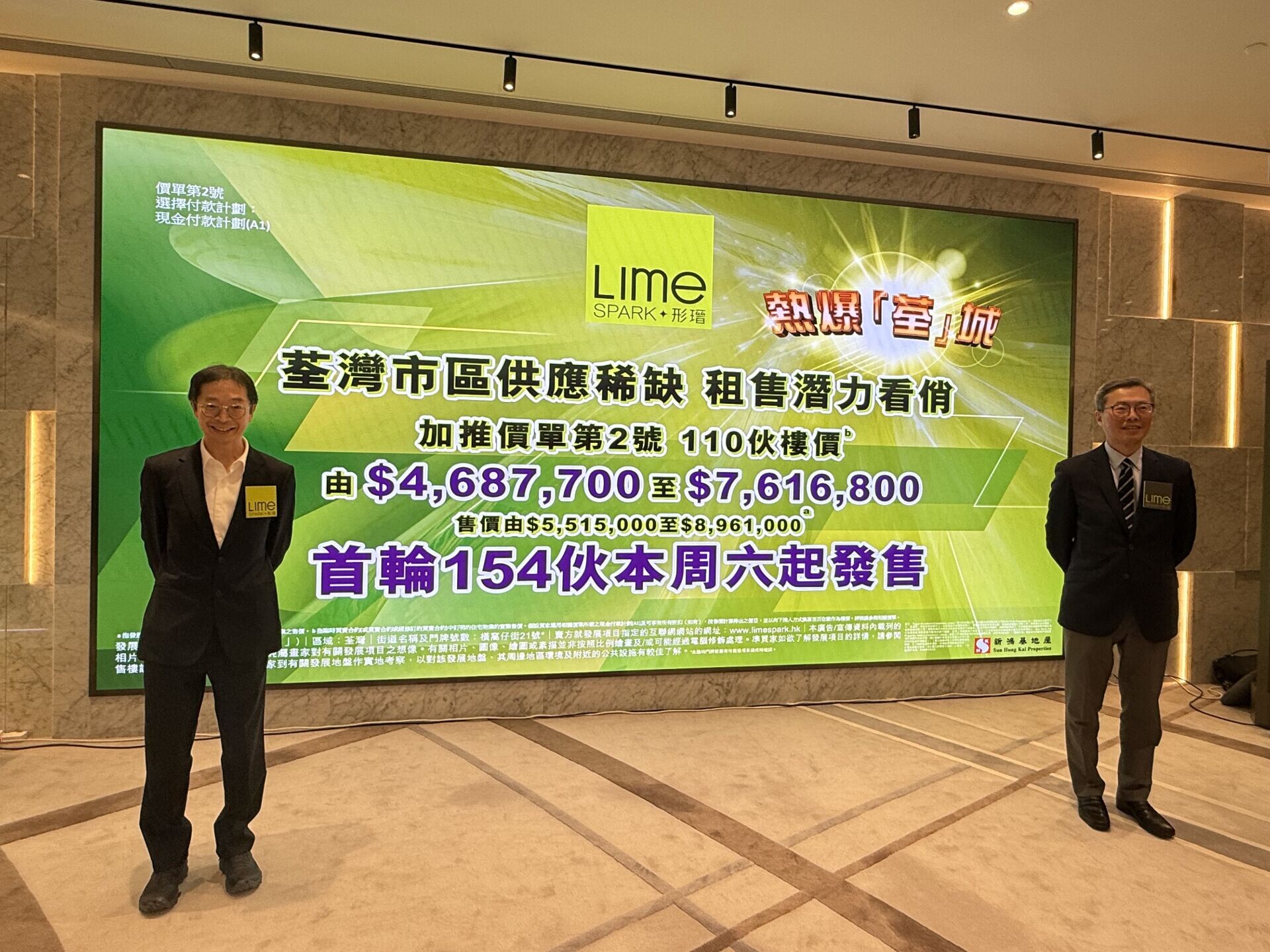 Two men in dark suits stand beside a large green Lime promotional banner in a marble lobby, smiling at the camera.