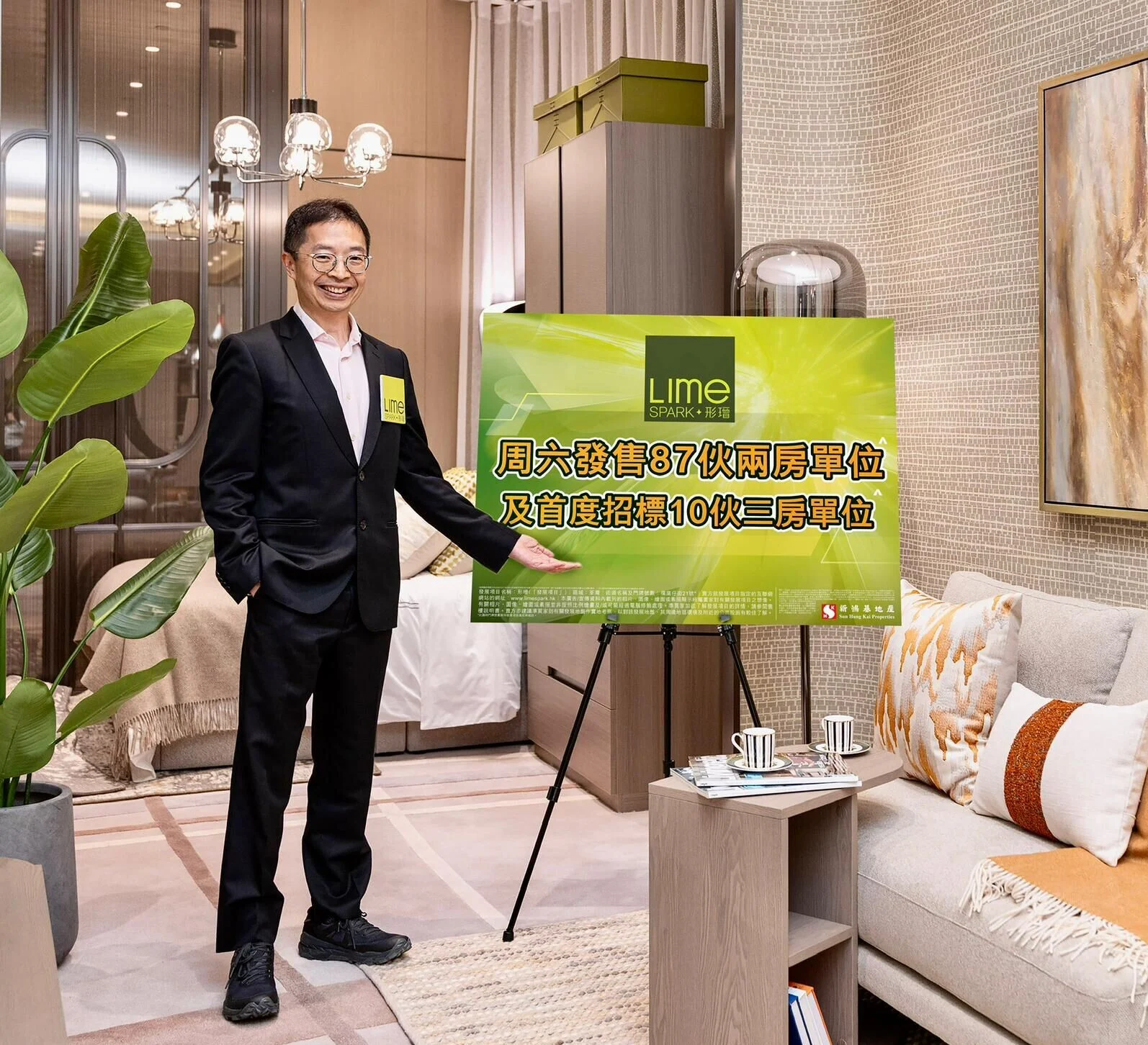 Man in a dark suit standing in a stylish showroom, pointing to a large green promotional sign that reads Lime Spark in Chinese and English.