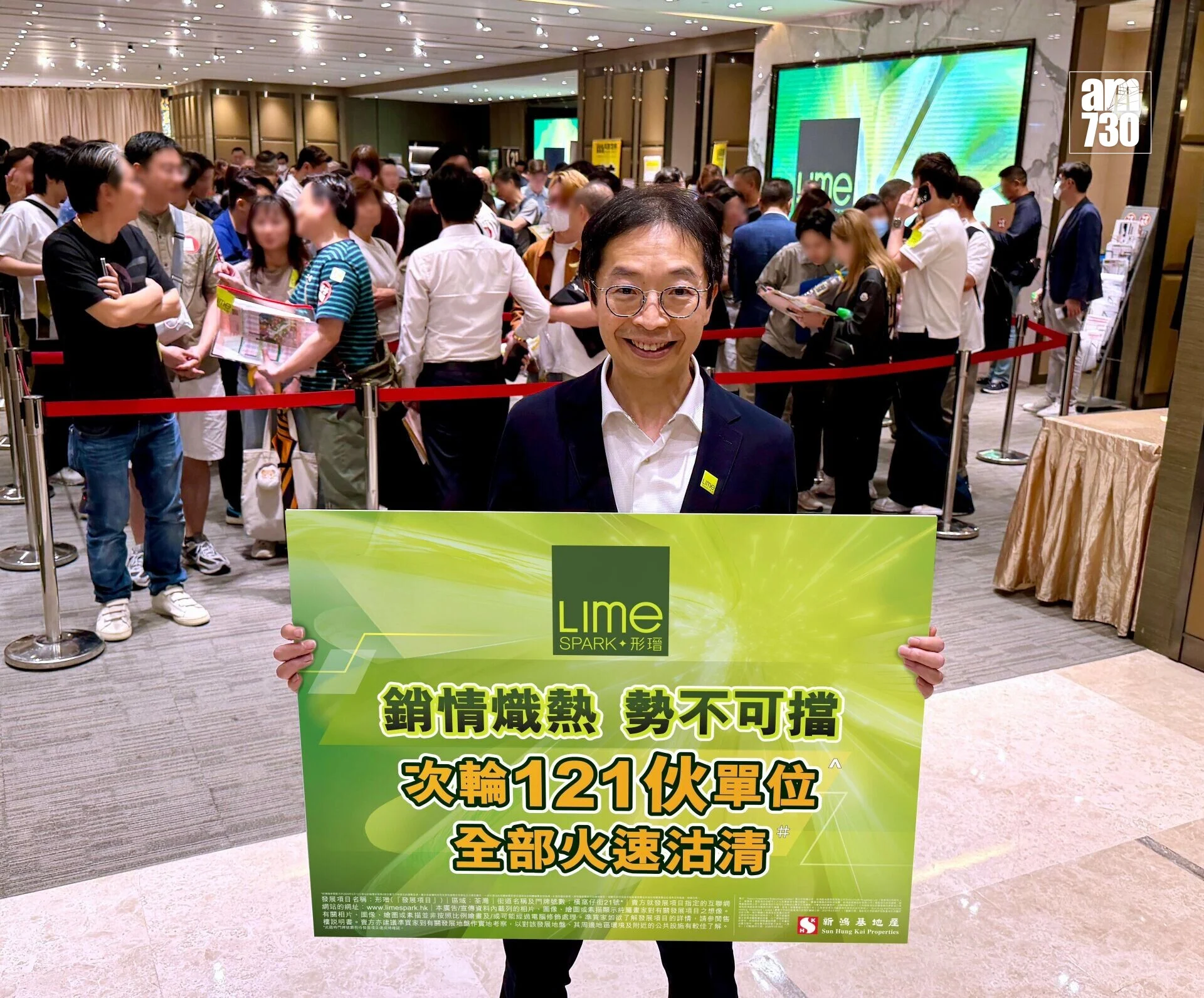 Smiling man in a suit holds a bright green Lime Spark promotional board as a crowded queue forms behind him in an indoor event space.
