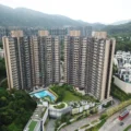 Aerial view of a U shaped cluster of high rise apartment buildings with a central pool and landscaping set against hills in the background