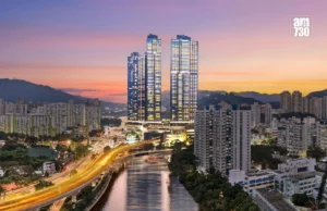 Twin glass skyscrapers dominate a city skyline at sunset beside a river with a curved highway and surrounding high rise apartments AM730 logo in the top right corner