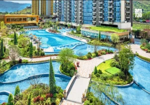Luxurious resort complex with winding blue pools walkways and surrounding greenery beside high rise buildings