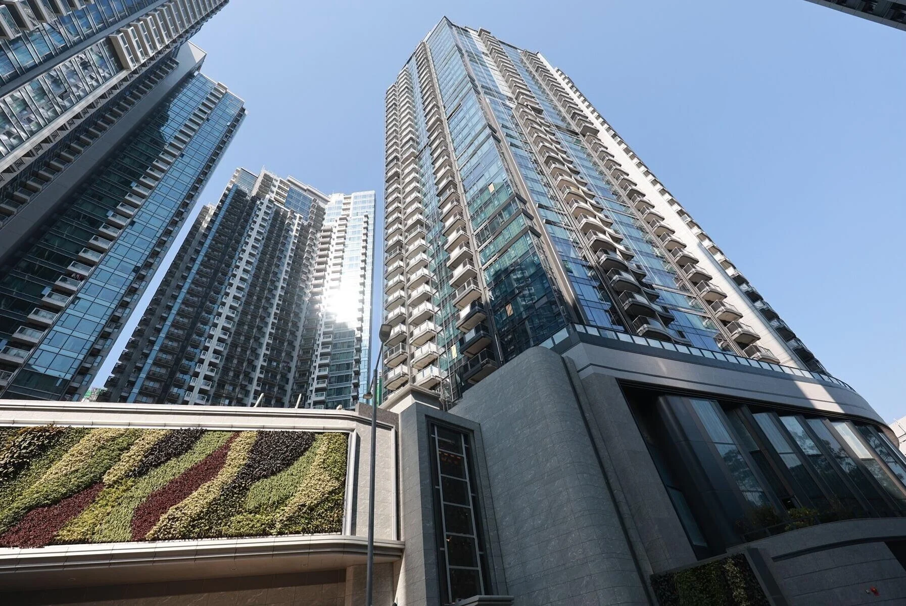Low-angle view of modern glass skyscrapers reaching into a clear blue sky.