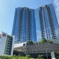 Blue glass high rise building with two connected towers against a clear blue sky am730 logo visible in the top right corner