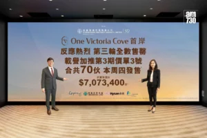 Two people in business attire pose on a stage in front of a large gradient banner with Chinese text and sponsor logos likely at a promotional event